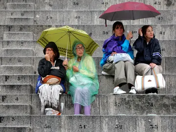 Gente protegiéndose de la lluvia con paraguas y chubasqueros Gente protegiéndose de la lluvia con paraguas y chubasqueros