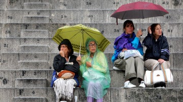 Gente protegiéndose de la lluvia con paraguas y chubasqueros