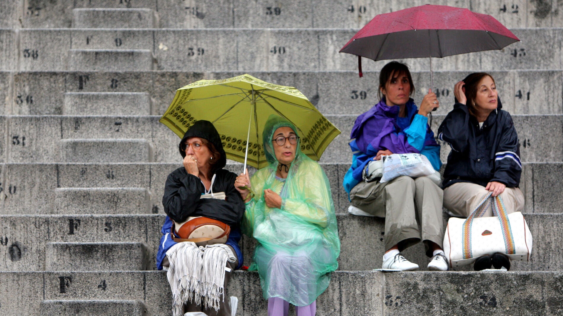Gente protegi&eacute;ndose de la lluvia con paraguas y chubasqueros