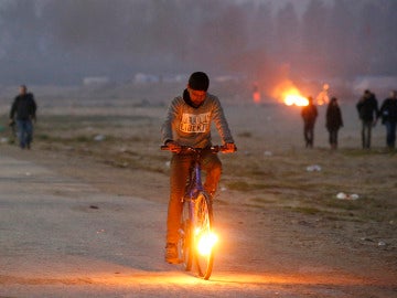 Un niño en bicicleta en el campamento de Calais