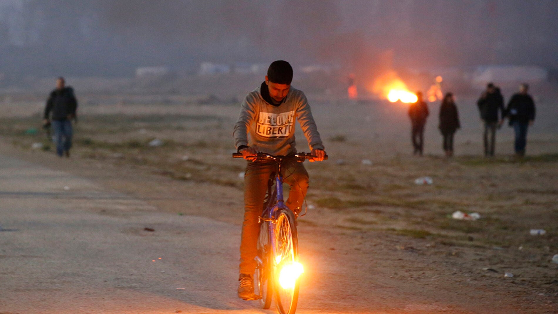 Un ni&ntilde;o en bicicleta en el campamento de Calais