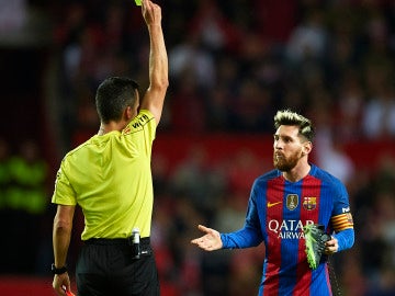 Messi ve la cartulina amarilla mientras sujeta su bota con la mano