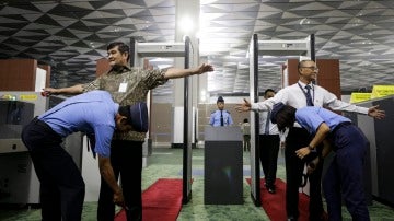 Oficiales de seguridad inspeccionan a los pasajeros en un punto de control de un aeropuerto