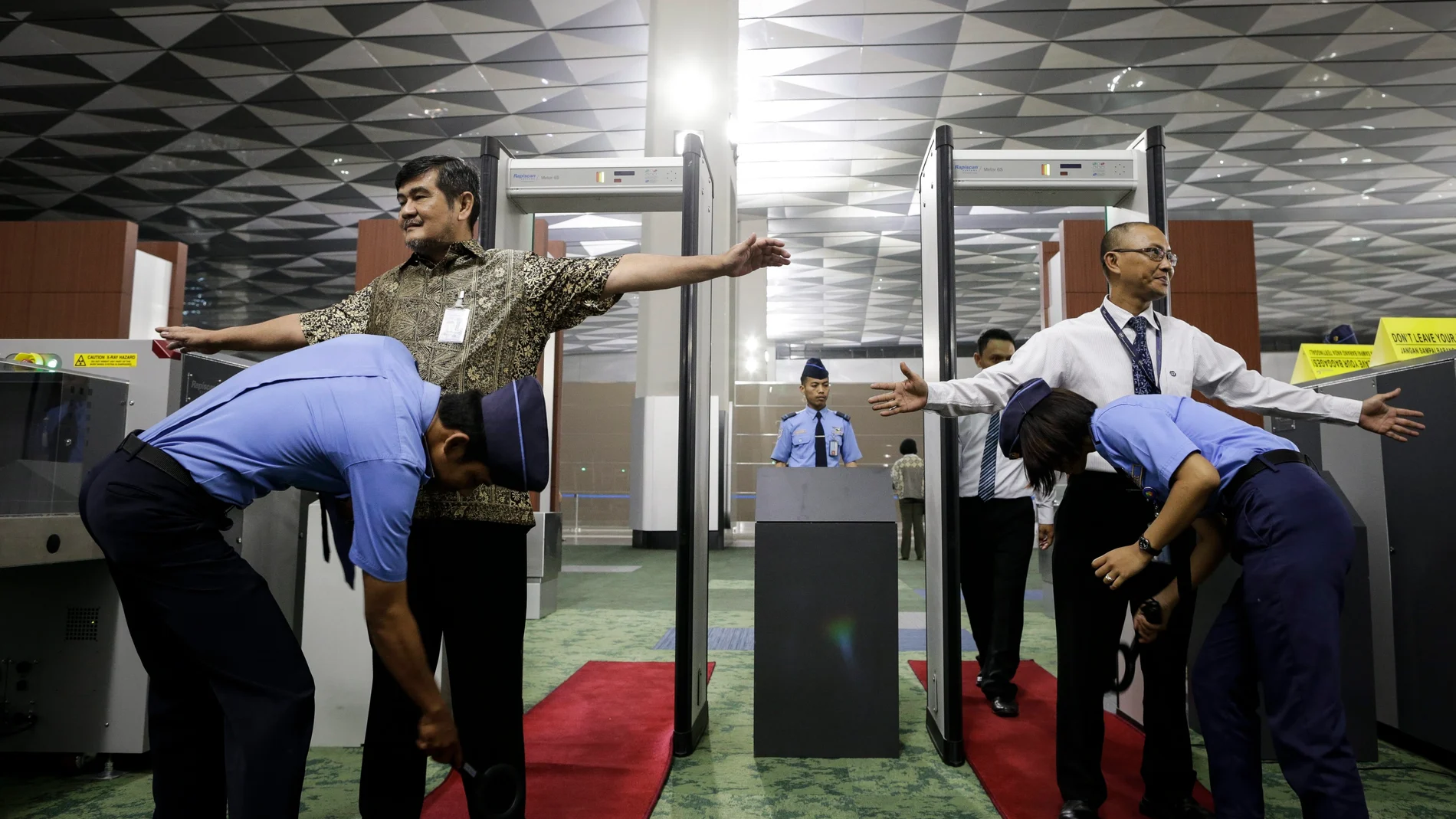 Oficiales de seguridad inspeccionan a los pasajeros en un punto de control de un aeropuerto Oficiales de seguridad inspeccionan a los pasajeros en un punto de control de un aeropuerto