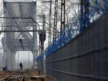 Un policía fronterizo inspecciona una vía de tren Un policía fronterizo inspecciona una vía de tren