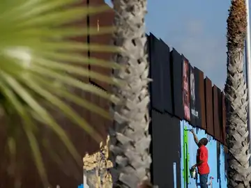 Un voluntario pinta murales en la cerca que marca el límite en la frontera entre EEUU y México Un voluntario pinta murales en la cerca que marca el límite en la frontera entre EEUU y México