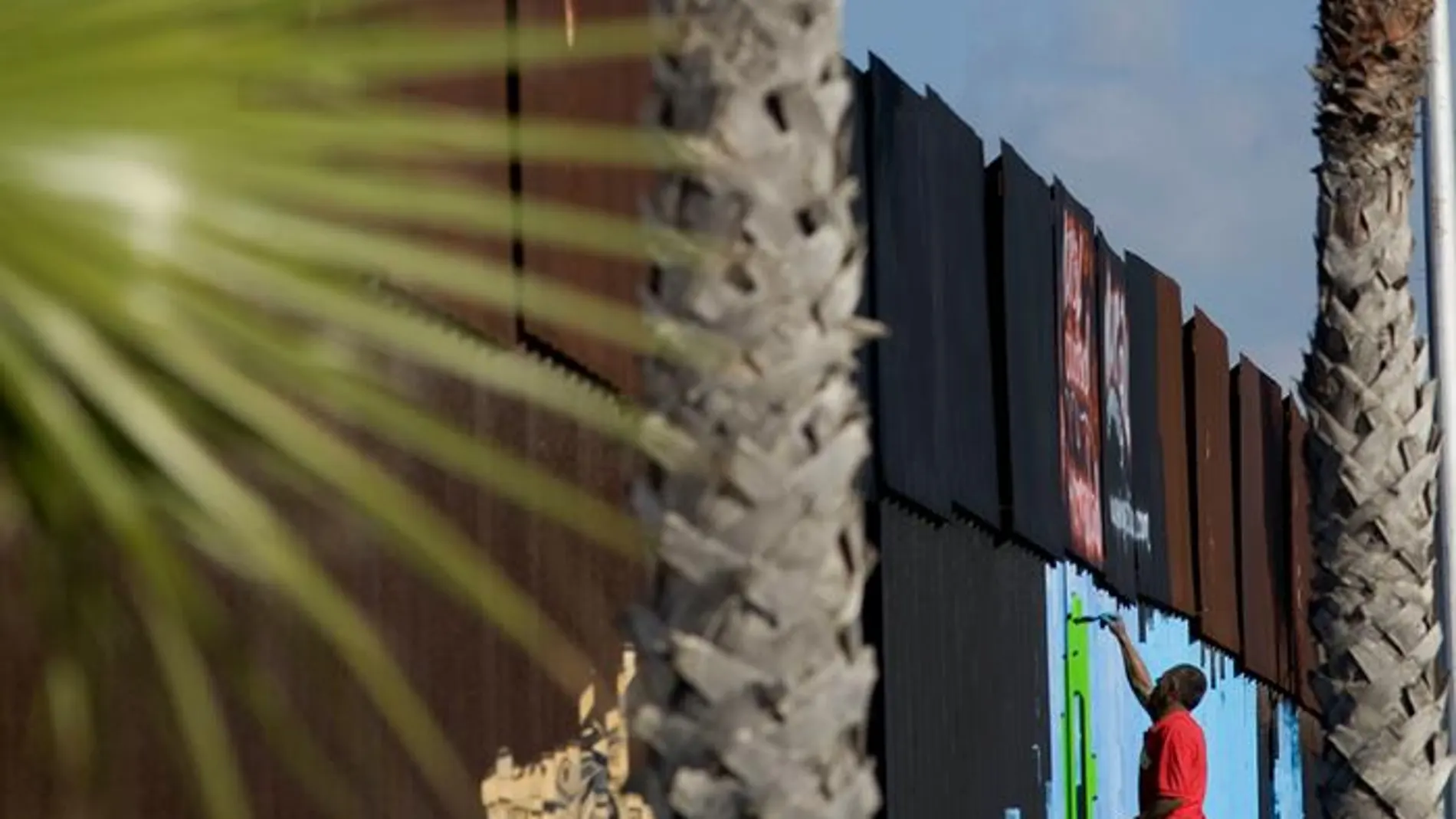 Un voluntario pinta murales en la cerca que marca el límite en la frontera entre EEUU y México Un voluntario pinta murales en la cerca que marca el límite en la frontera entre EEUU y México