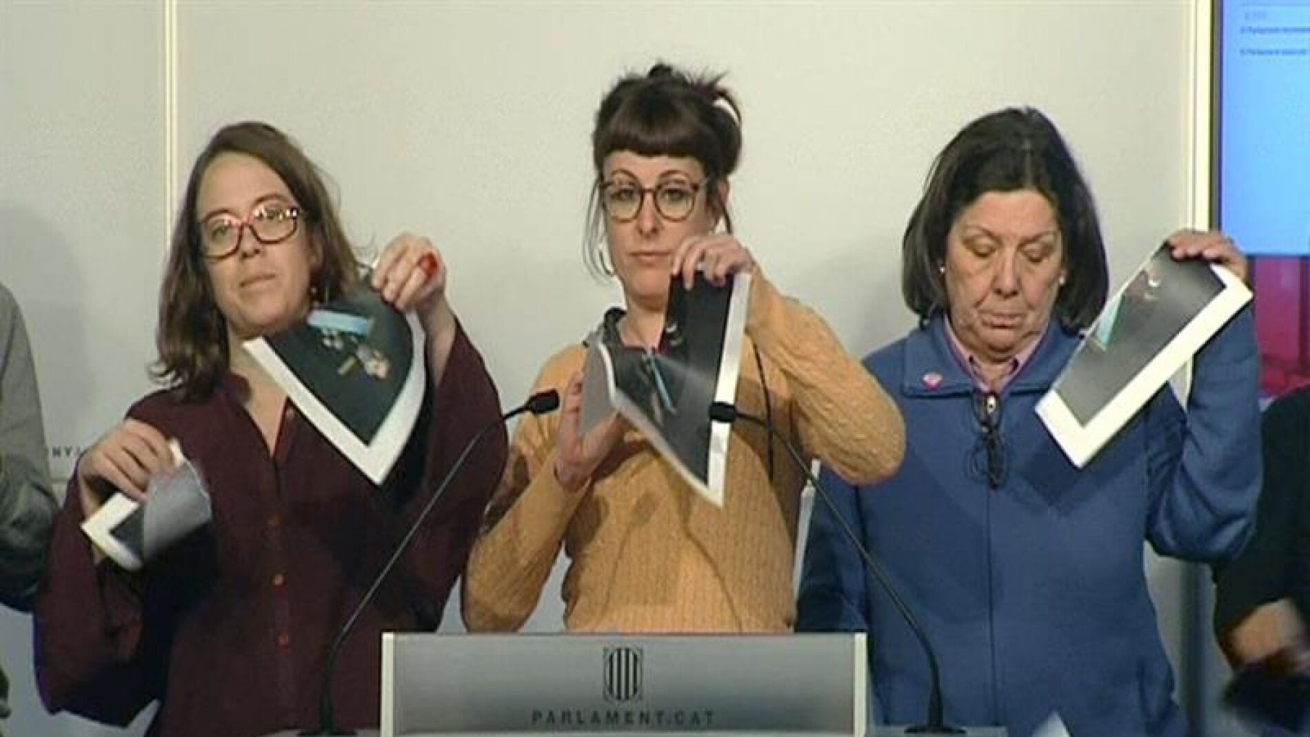 Imagen de televisi&oacute;n de varias diputadas de la CUP en el Parlament que rompen fotograf&iacute;as del Rey, durante una rueda de prensa