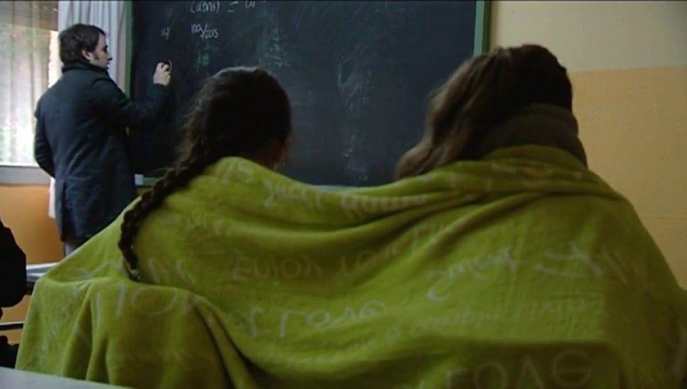 Imagen de dos alumnas dando clase abrigadas con una manta para soportar el frío