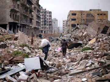 Varios sirios caminan sobre las ruinas de Alepo