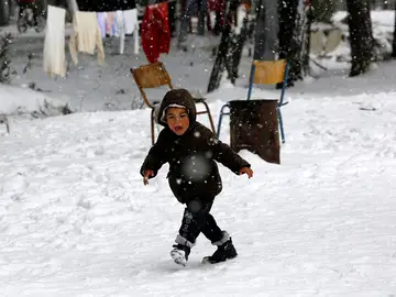 Un niño refugiado caminando sobre la nieve Un niño refugiado caminando sobre la nieve