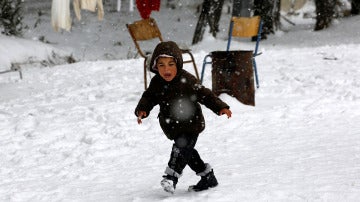 Un niño refugiado caminando sobre la nieve 