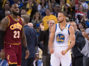 Stephen Curry celebra una canasta ante la mirada de LeBron James