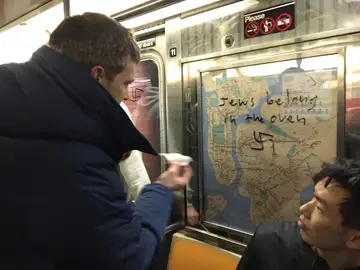 Un pasajero del metro de Nueva York elimina un mensaje de odio hacia judíos en uno de los vagones Un pasajero del metro de Nueva York elimina un mensaje de odio hacia judíos en uno de los vagones