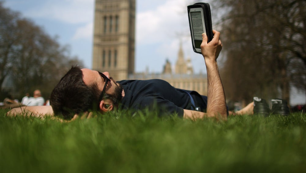 Un lector tumbado leyendo un libro electrónico