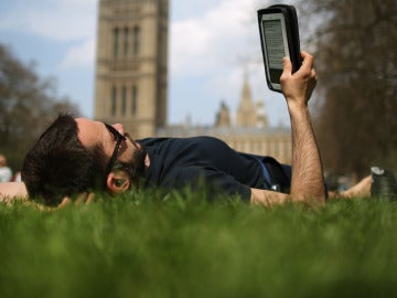 Un lector tumbado leyendo un libro electrónico