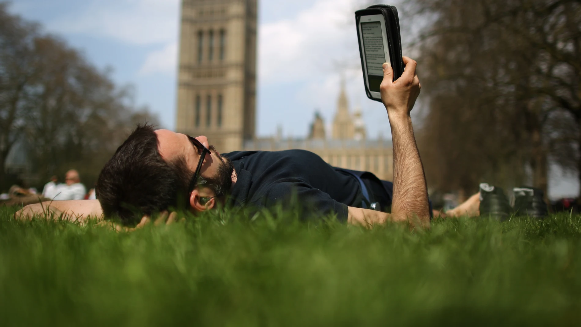 Un lector tumbado leyendo un libro electrónico Un lector tumbado leyendo un libro electrónico