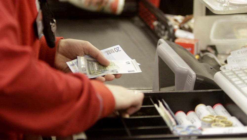 Una cajera de un supermercado devuelve el cambio a un cliente