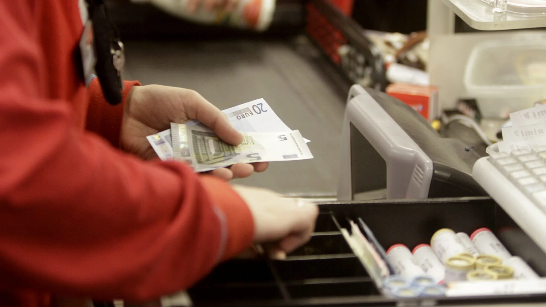 Una cajera de un supermercado devuelve el cambio a un cliente Una cajera de un supermercado devuelve el cambio a un cliente