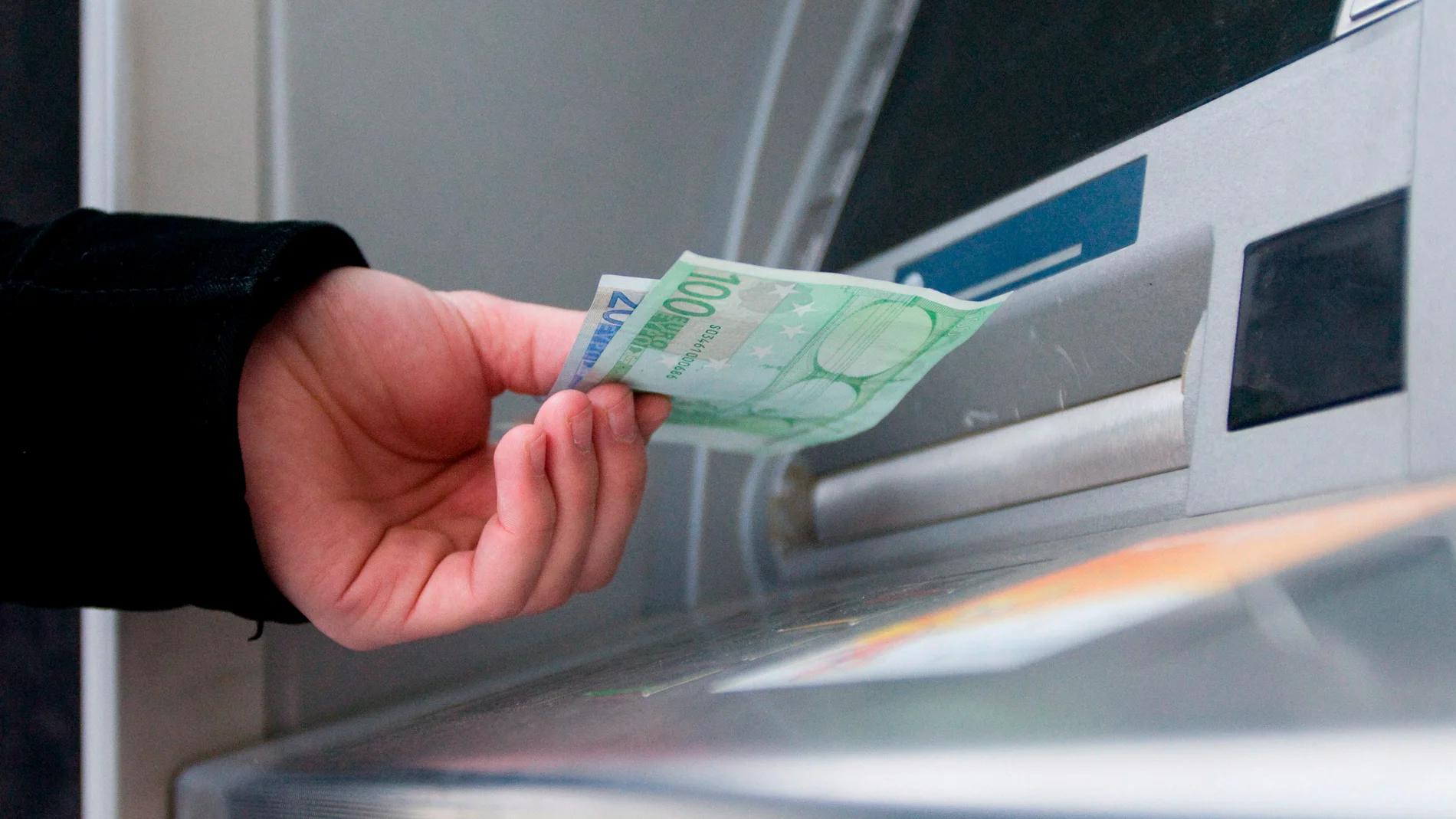 Un hombre saca dinero del cajero automático Un hombre saca dinero del cajero automático