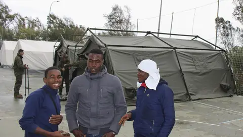 Un grupo de inmigrantes al lado de una tienda de campaña Un grupo de inmigrantes al lado de una tienda de campaña