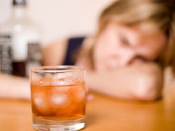 Una mujer ante un vaso con alcohol