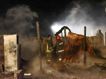 Bomberos tratan de extinguir el fuego en un campamento de inmigrantes en la localidad de Rignano Garganico, en Italia