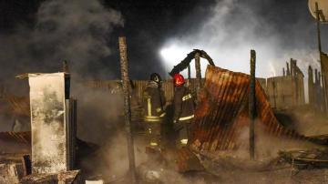 Bomberos tratan de extinguir el fuego en un campamento de inmigrantes en la localidad de Rignano Garganico, en Italia