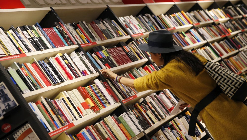 Una mujer mira libros en los estanterías de una librería