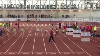 Un juez se mete en una pista de atletismo en plena carrera de 60 metros lisos