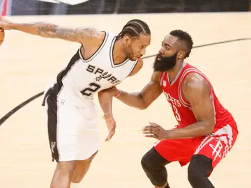 Kawhi Leonard sostiene el balón con una mano ante la defensa de James Harden Kawhi Leonard sostiene el balón con una mano ante la defensa de James Harden