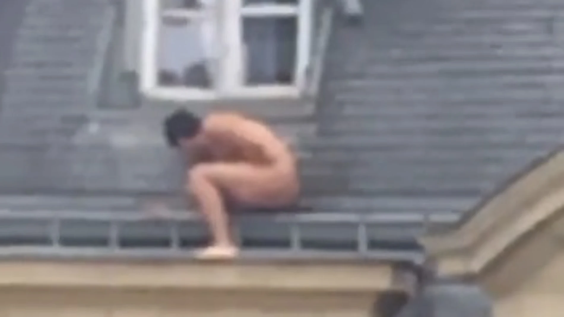 Un hombre desnudo se esconde en el alféizar de una ventana
