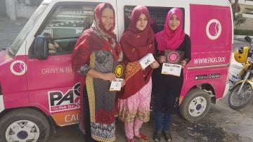 Tres mujeres pakistaníes posan junto a uno de los taxis rosas que circulan para proteger a las mujeres del acoso