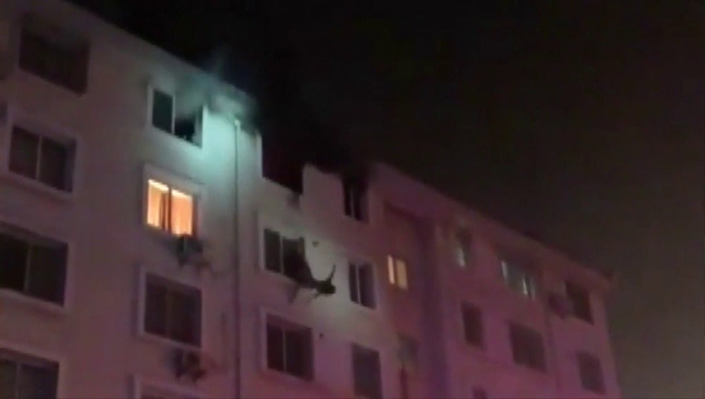 Frame 7.304987 de: Un bombero consigue rescatar "al vuelo" a una mujer cuando escapaba de un incendio por una fachada 