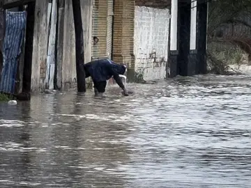 Una persona recoge agua en la puerta de su vivienda, en el barrio del Matadero de Huelva Una persona recoge agua en la puerta de su vivienda, en el barrio del Matadero de Huelva