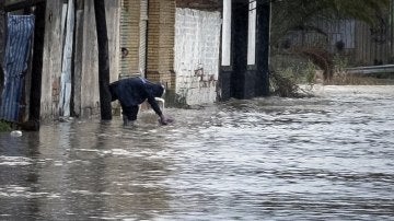 Una persona recoge agua en la puerta de su vivienda, en el barrio del Matadero de Huelva
