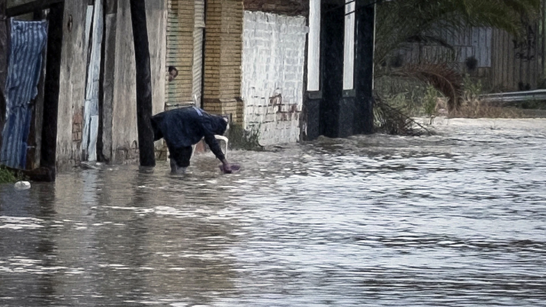 Una persona recoge agua en la puerta de su vivienda, en el barrio del Matadero de Huelva Una persona recoge agua en la puerta de su vivienda, en el barrio del Matadero de Huelva