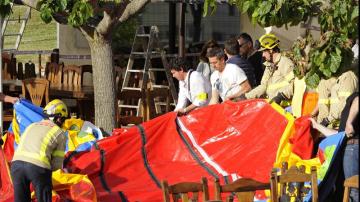 Varios operarios y bomberos retiran el castillo hinchable del restaurante Mas Oller