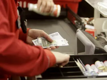 Una cajera devuelve el cambio a un cliente Una cajera devuelve el cambio a un cliente