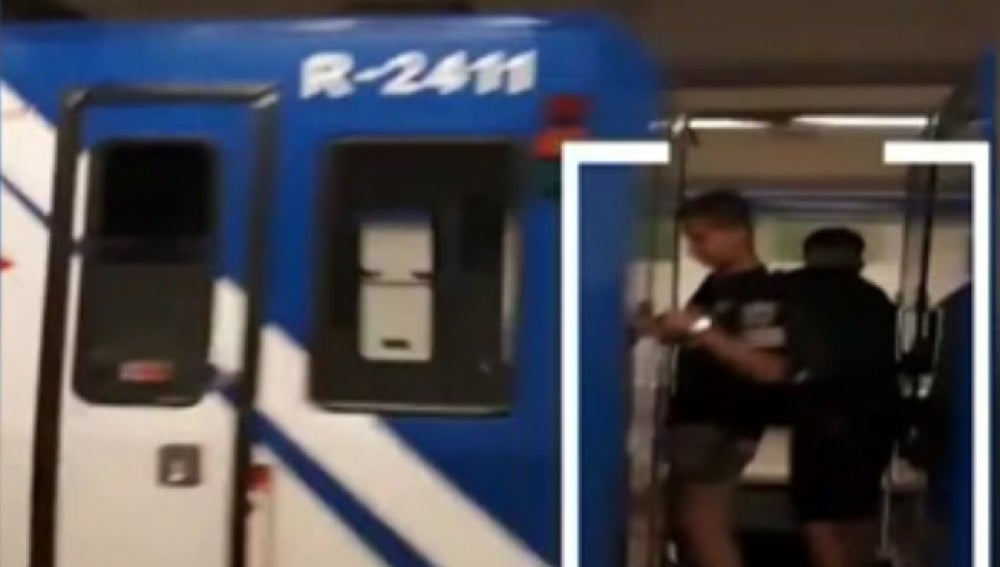 Dos niños viajan entre dos vagones del Metro de Madrid