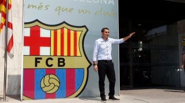 Ernesto Valverde saluda a la prensa mientras posa con el escudo del Barça detrás