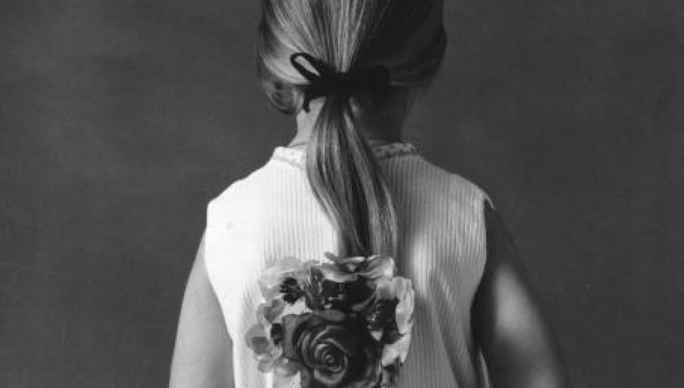 Una niña de espalda con una flor
