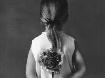 Una niña de espalda con una flor