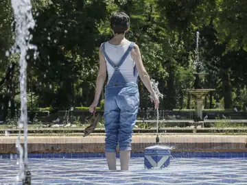 Una chica se refresca del intenso calor en una fuente del parque de Maria Luisa de Sevilla Una chica se refresca del intenso calor en una fuente del parque de Maria Luisa de Sevilla