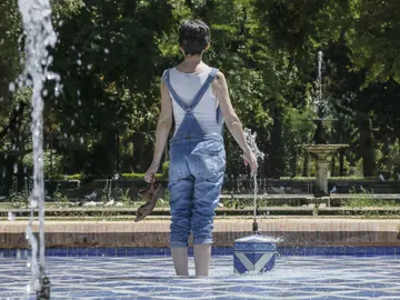 Una chica se refresca del intenso calor en una fuente del parque de Maria Luisa de Sevilla Una chica se refresca del intenso calor en una fuente del parque de Maria Luisa de Sevilla