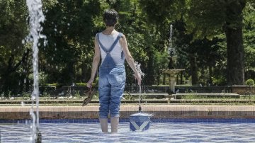 Una chica se refresca del intenso calor en una fuente del parque de Maria Luisa de Sevilla