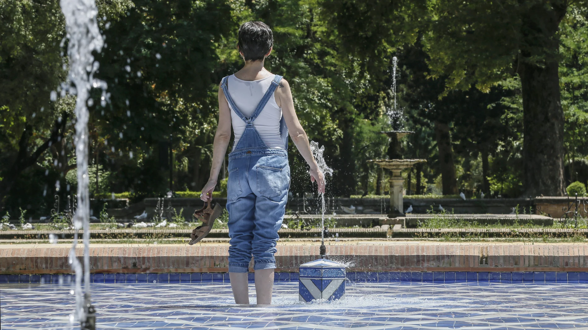 Una chica se refresca del intenso calor en una fuente del parque de Maria Luisa de Sevilla Una chica se refresca del intenso calor en una fuente del parque de Maria Luisa de Sevilla