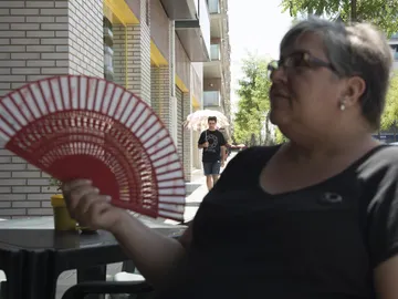 Un mujer se da aire con un abanico Un mujer se da aire con un abanico