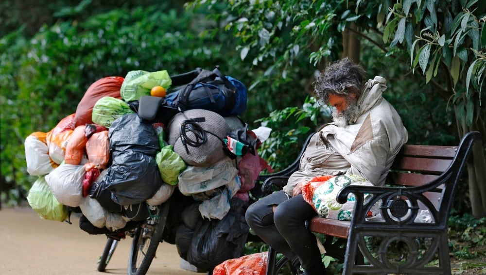 Un indigente durmiendo en un banco