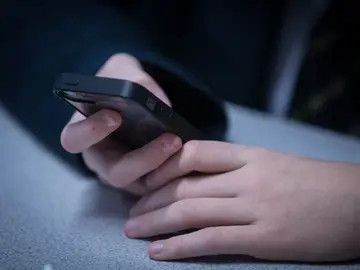 Un niño consulta un teléfono móvil (Archivo) Un niño consulta un teléfono móvil (Archivo)